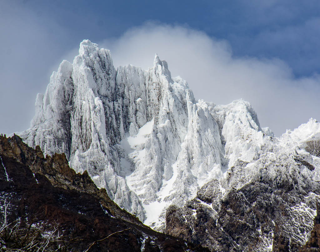 Jagged, rocky, snow-covered mountains, bare of vegetation, against a blue sky